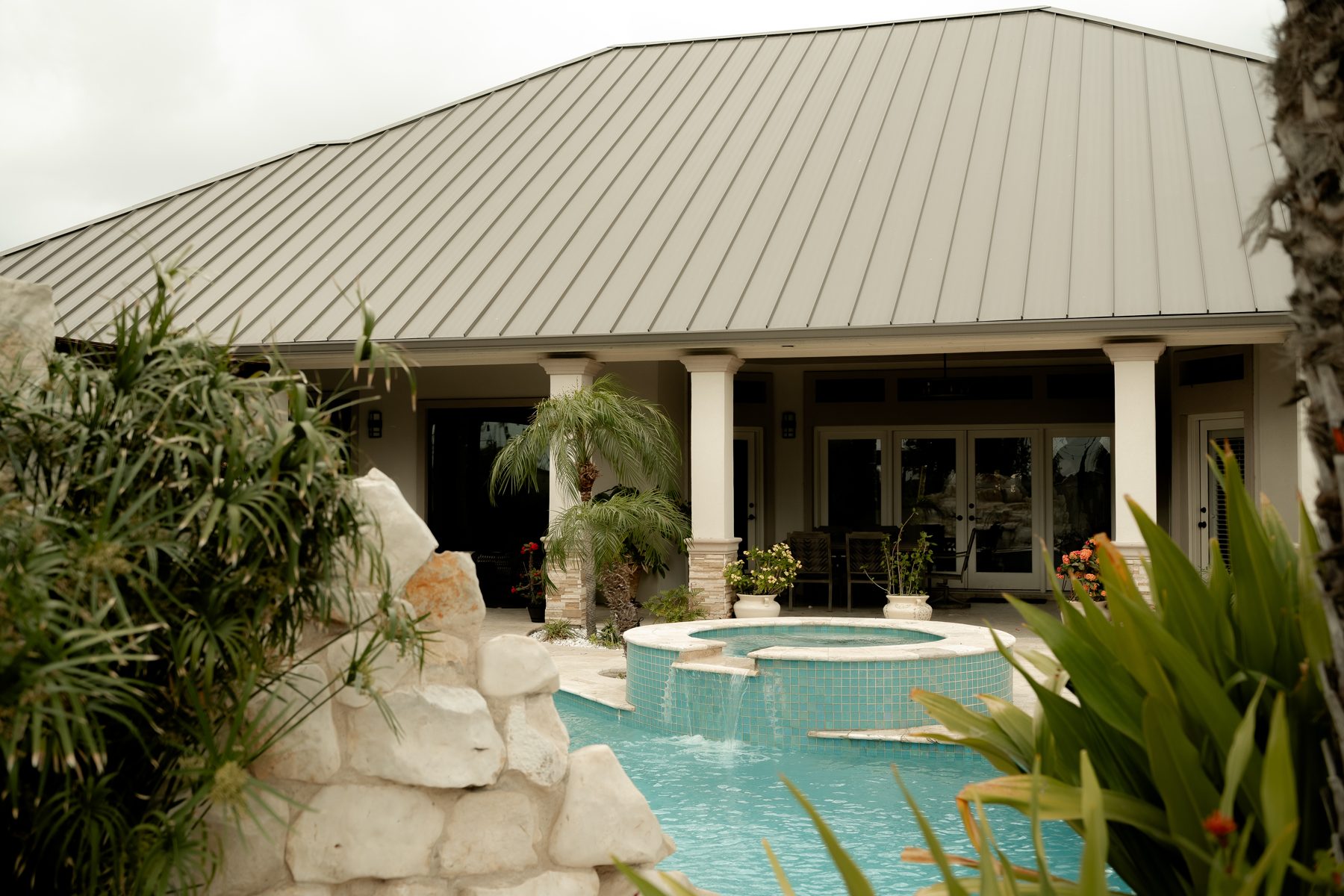 Pool area framed by tropical plants with house in background
