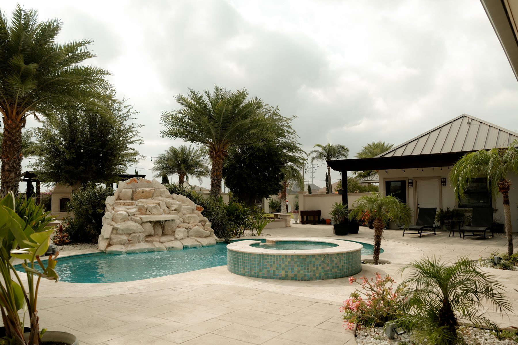 Full pool area with jacuzzi, waterfall, and palm trees